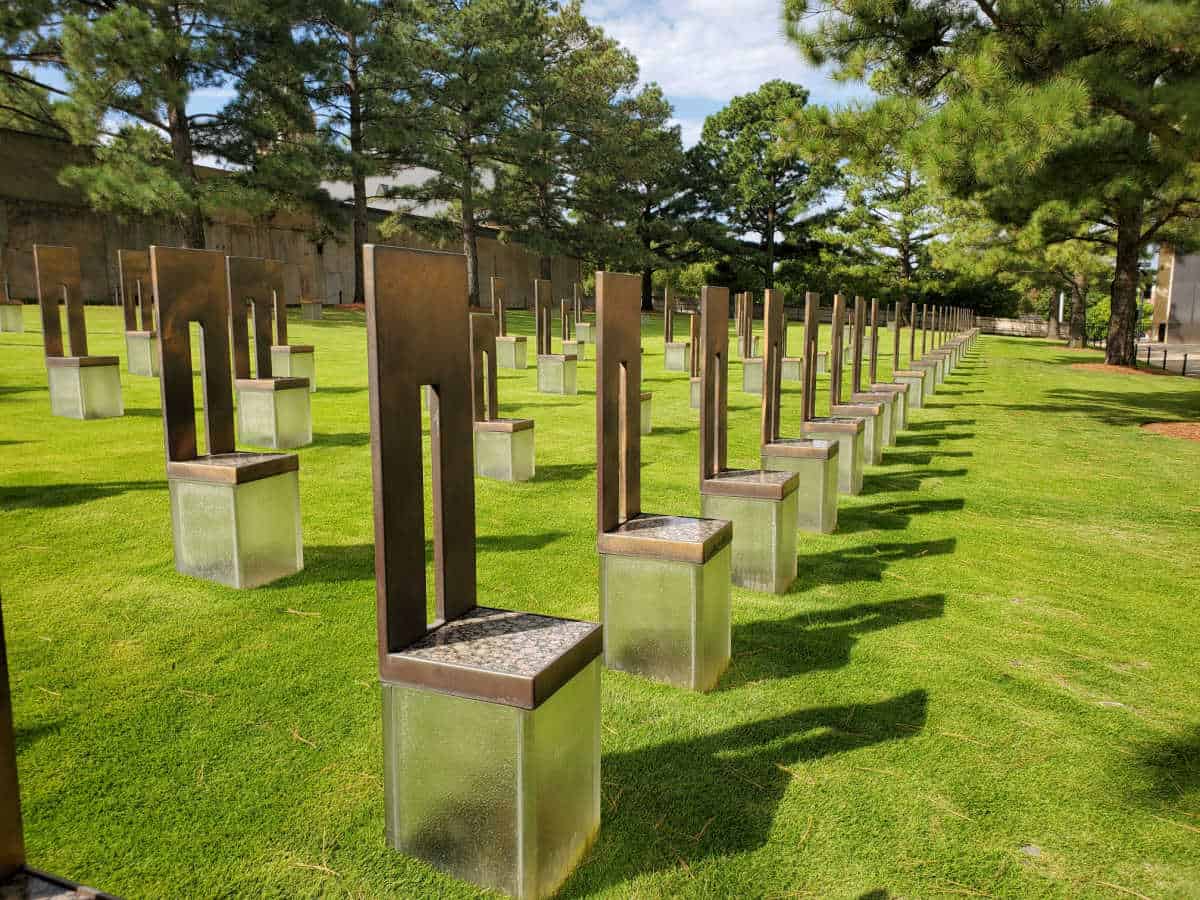 Rows of chair sculptures in an empty field with grass