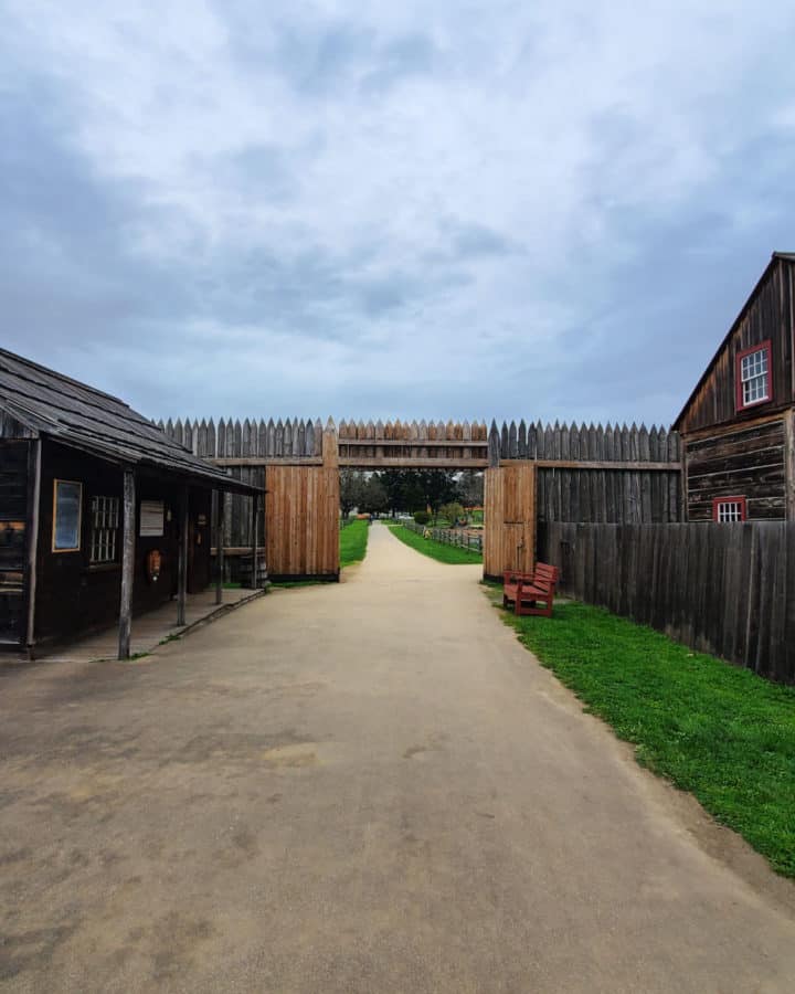 Walkway leading to a wooden fort entrance and wood buildings