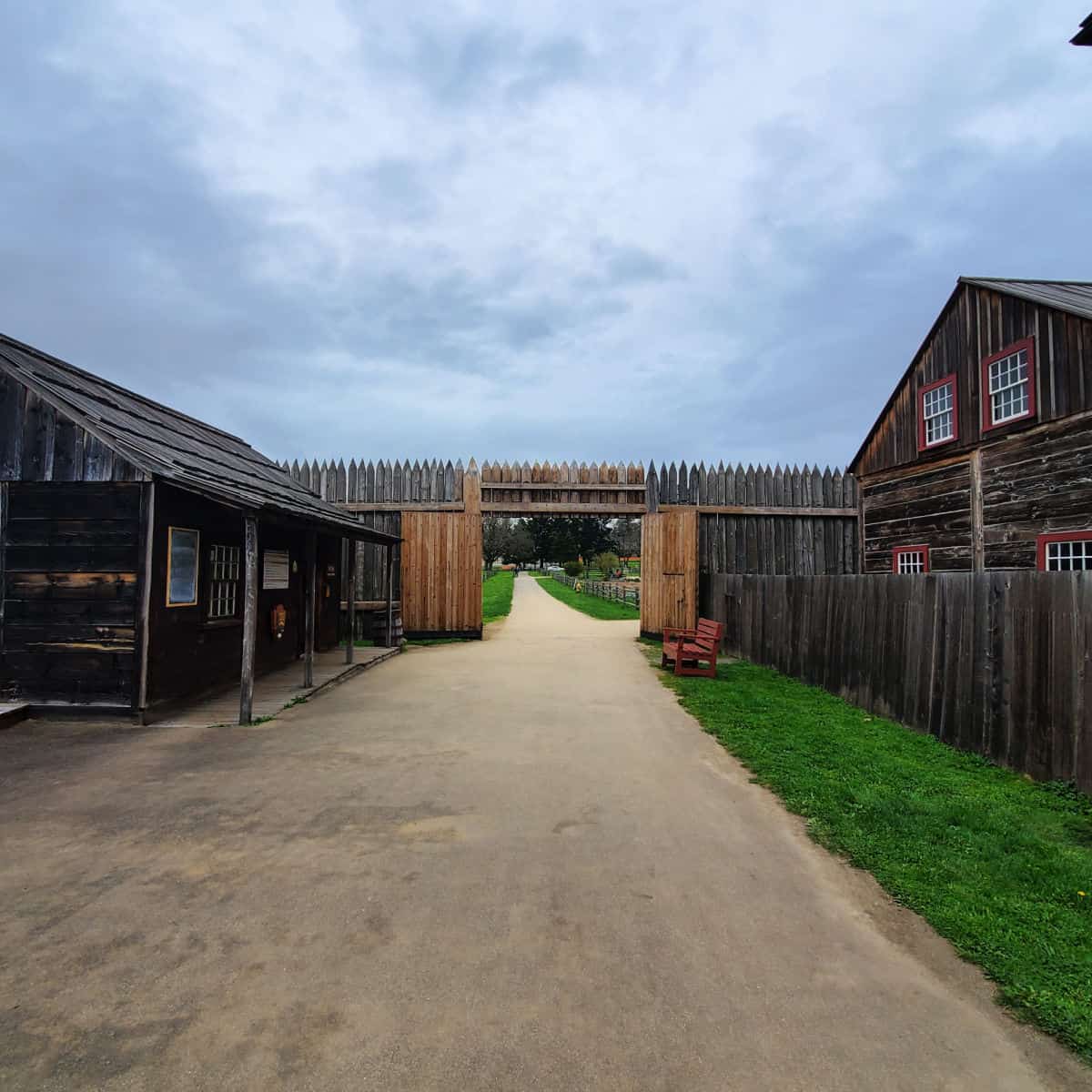 Walkway leading to a wooden fort entrance and wood buildings