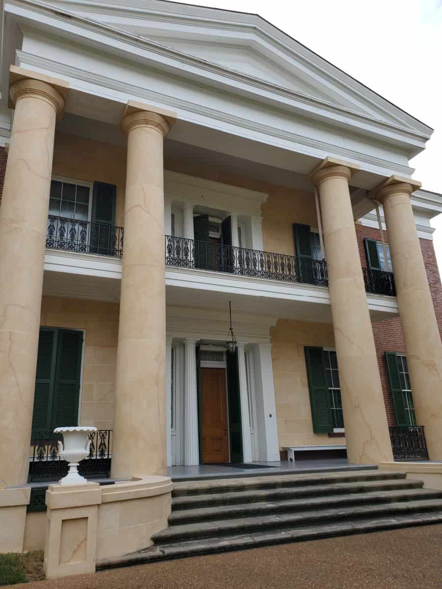 Two story Antebellum mansion with columns and stairs leading to the wood door