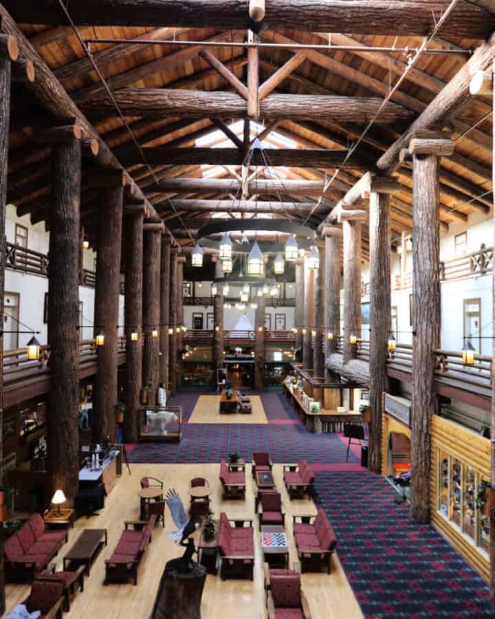 Historic Glacier Park Lodge lobby with giant tree trunk beams, seating, and chandelier