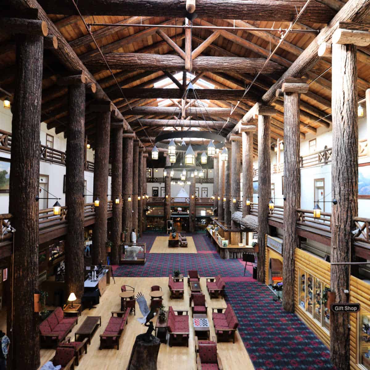 Historic Glacier Park Lodge lobby with giant tree trunk beams, seating, and chandelier
