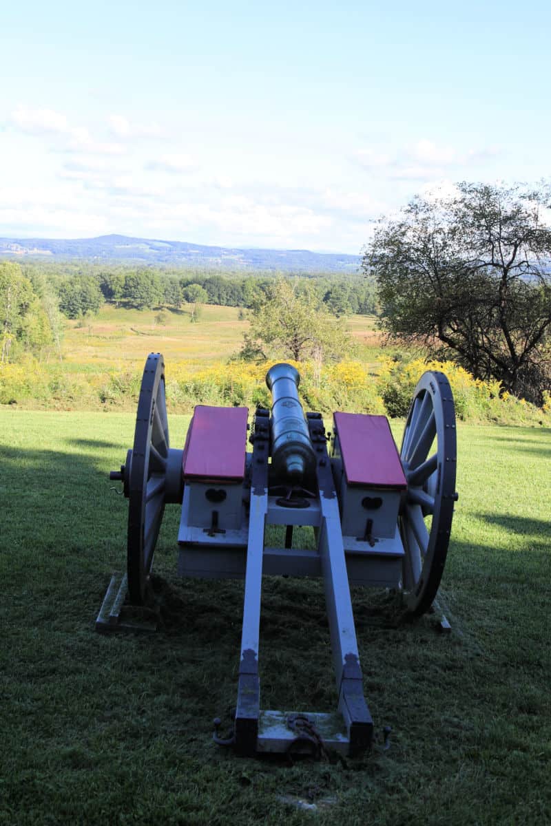 Historic cannon overlooking a field and mountains in the distance