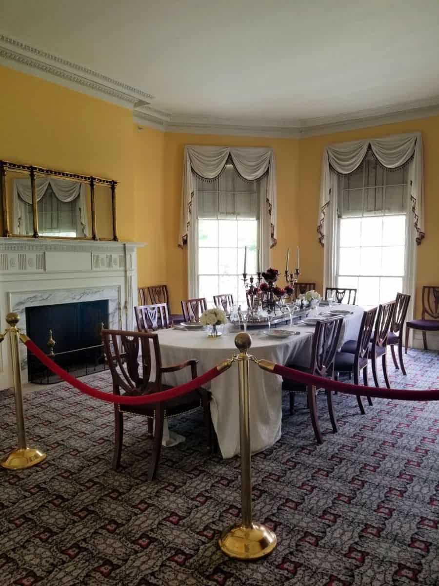 Historic dining room with large table, yellow walls, and dishes
