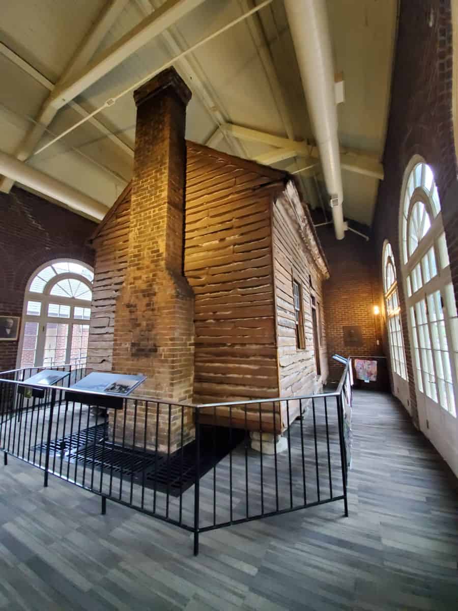 Historic wood cabin within the visitor center with path around it.