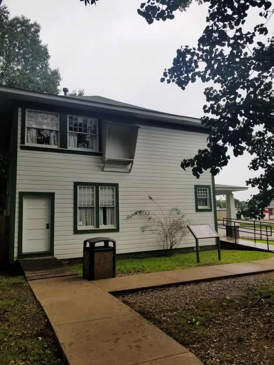 two story white house with windows, and garbage cans