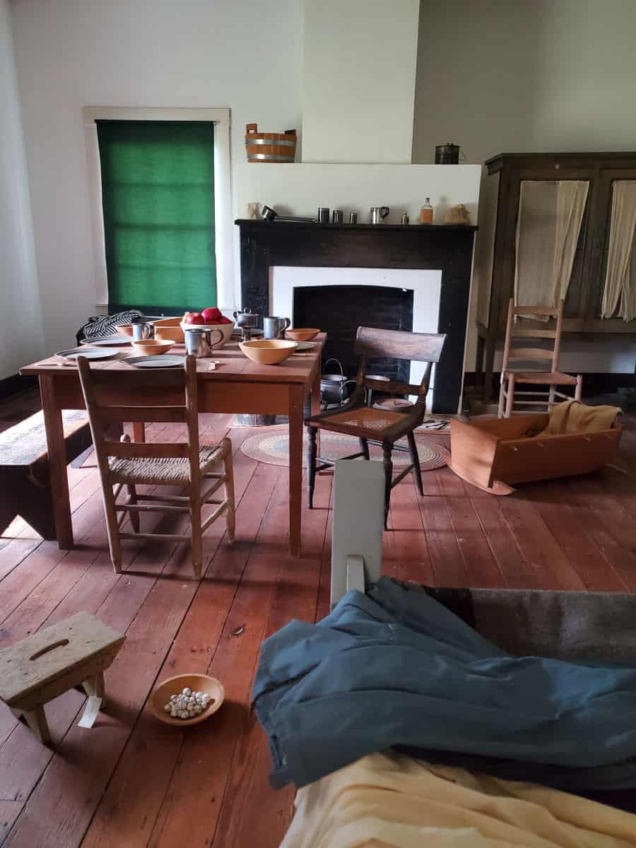 wooden table with place settings, chairs, and a bench near a fireplace.