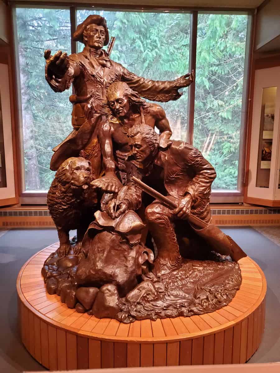 Statue of Lewis and Clark with their dog and another person in the visitor center on a wooden base