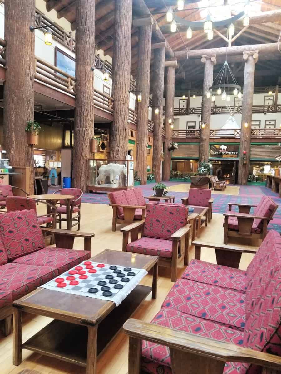 Checkers set on a wood table near comfy chairs in the Glacier Park Lodge lobby with a mountain goat in the background