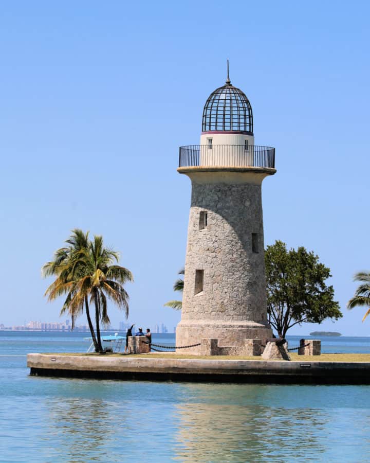 Boca Chita Key light house with palm trees and Miami in the background