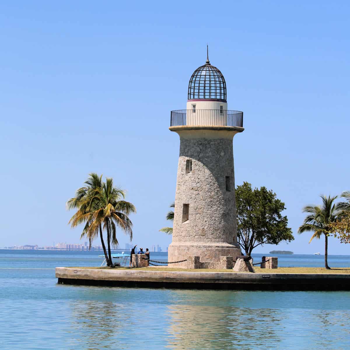 Boca Chita Key light house with palm trees and Miami in the background