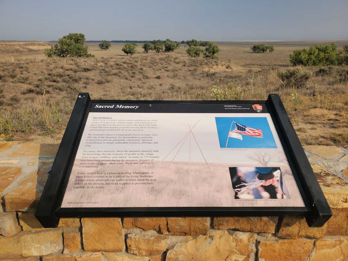 sacred memory interpretive panel overlooking a field with trees