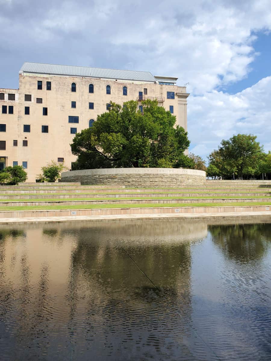 survivors tree in front of memorial museum building with the reflection pool