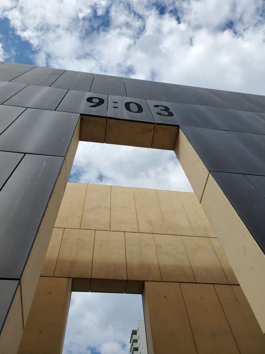 Looking up at the 9:03 tower with clouds in the sky