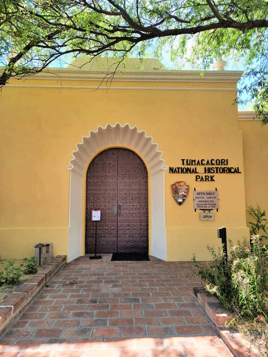 Bright yellow building with ornate door and Tumacacori National Historical Park sign