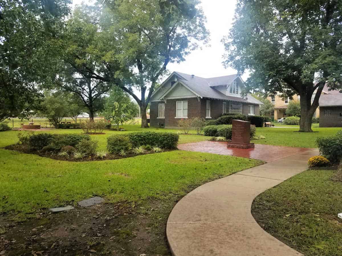 paved pathway leading back to the visitor center with grass and bushes 