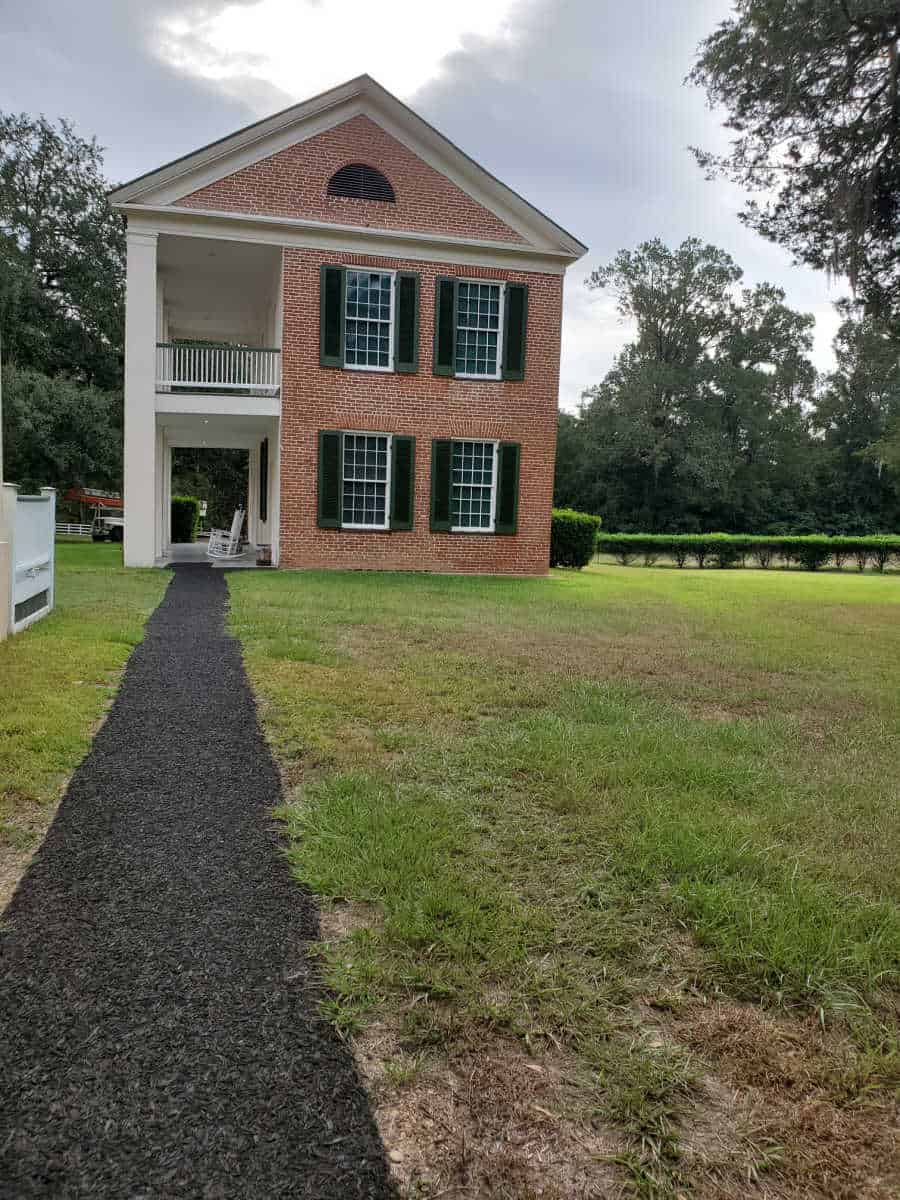 paved path to 2 story brick building with windows and balcony