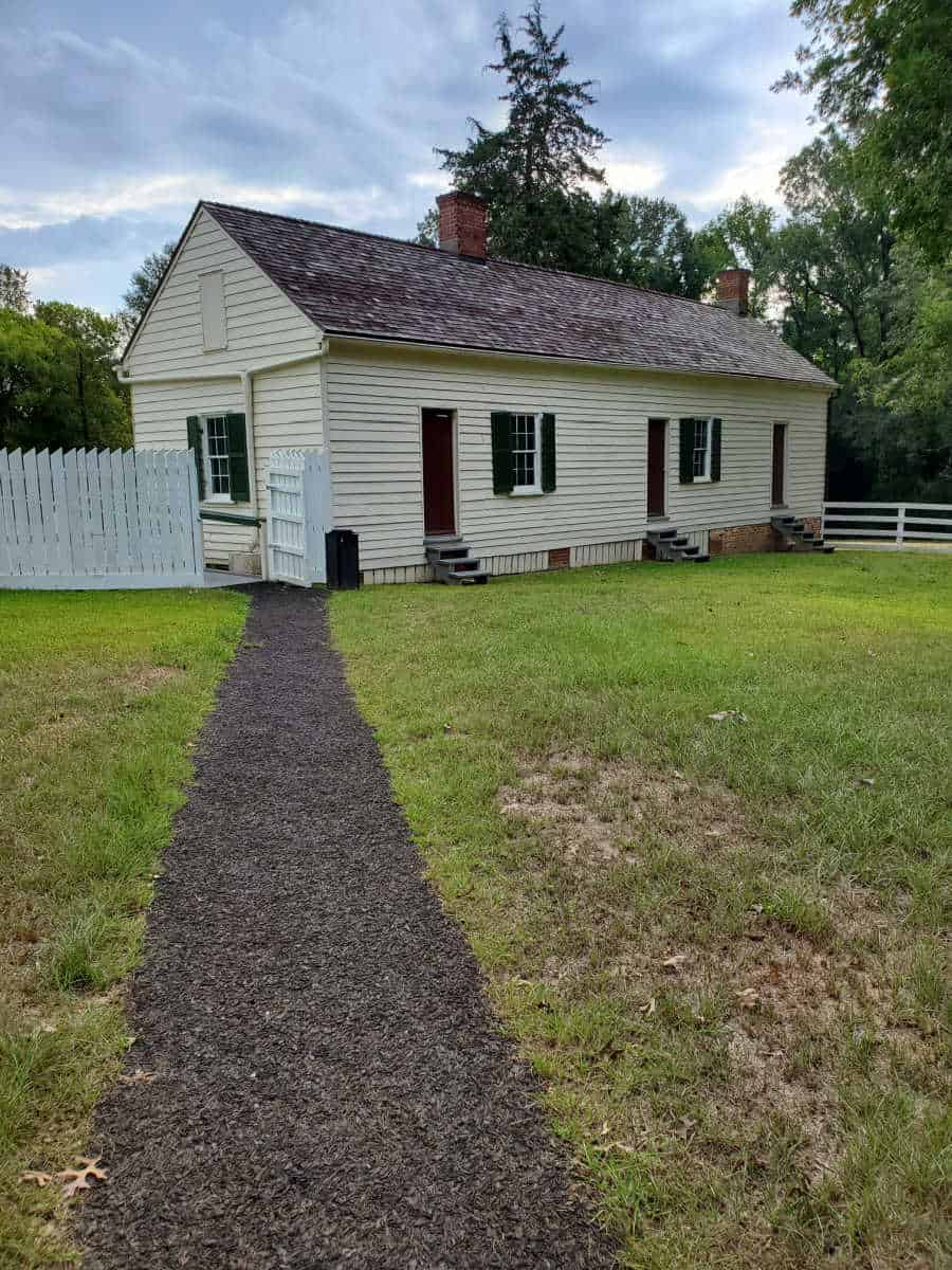 path leading to single story building with a white fence and multiple doors