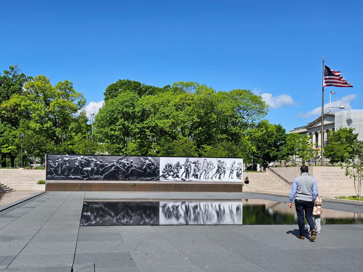 World War I memorial soldiers journey art reflecting in a pool with the American flag in the background