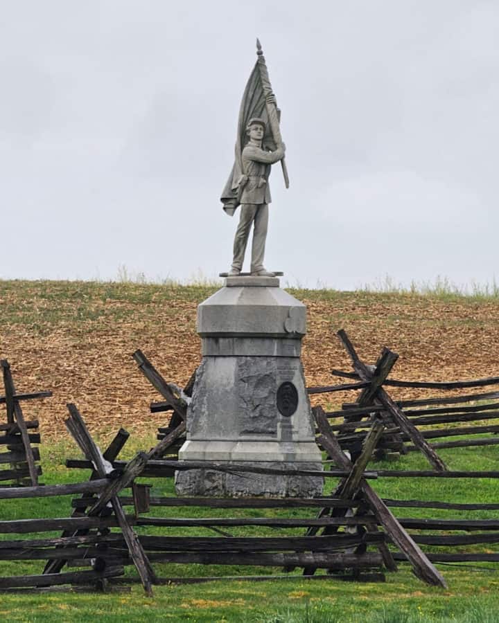 historic battlefield statue with a boy holding a flag surrounded by wooden fences in Antietam National Battlefield