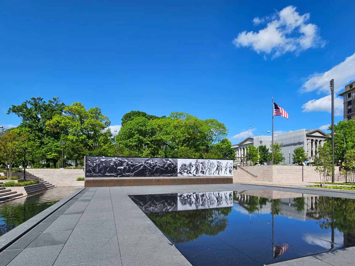 Reflecting pool with a soldiers journey reflecting and the American flag in the background