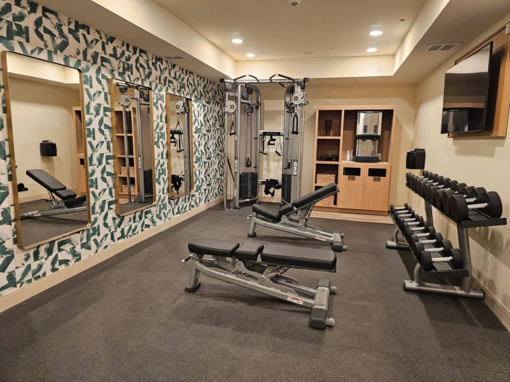 Free weights and benches in a fitness center with mirrors
