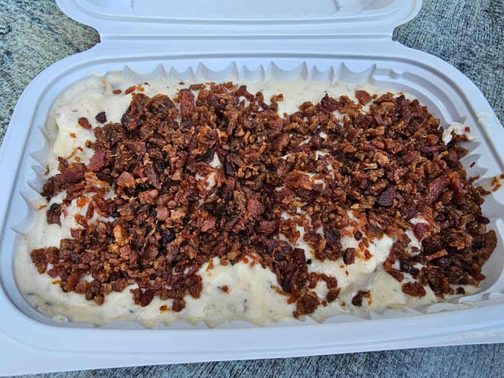 biscuits and gravy covered in crumbled bacon in a container