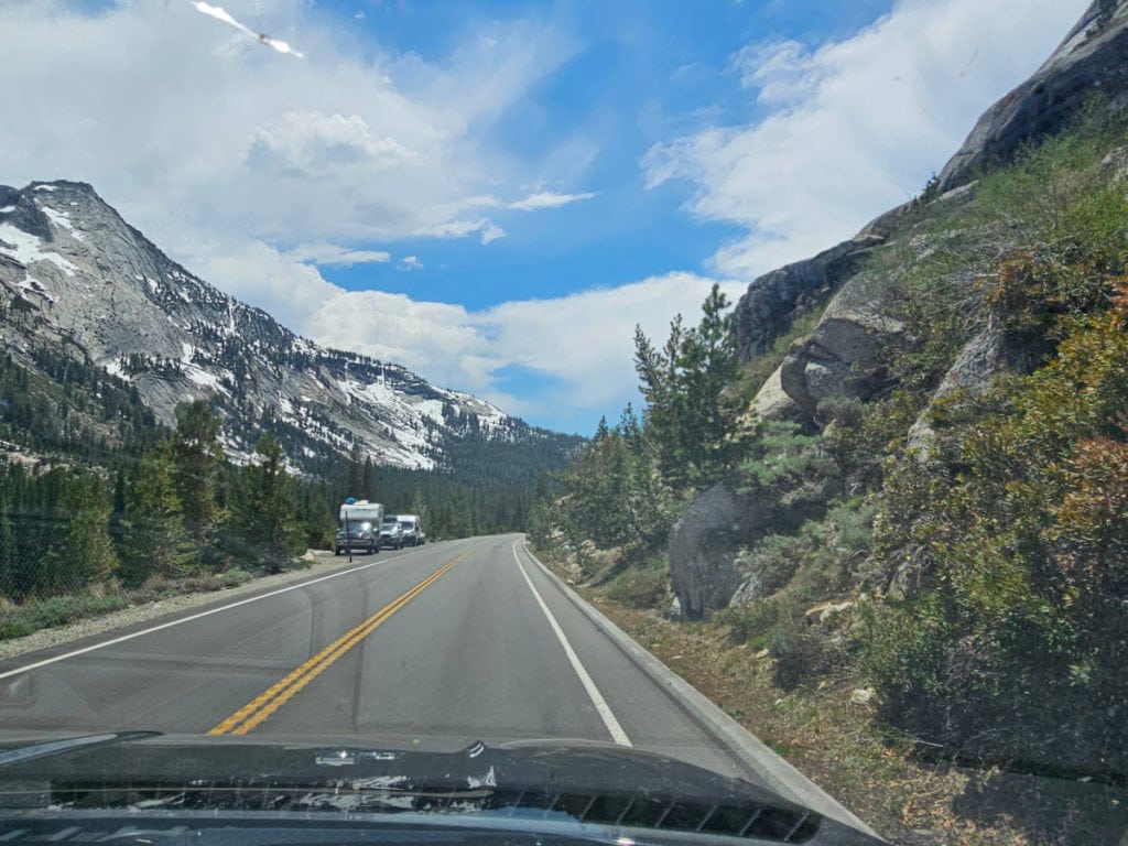 driving down tioga road with snow on the mountains