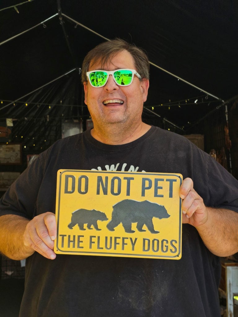 John holding a do not pet the fluffy dogs sign with bears on it
