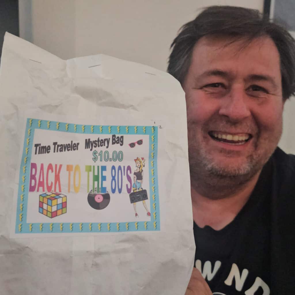 John holding a back to the 80s time traveler mystery bag
