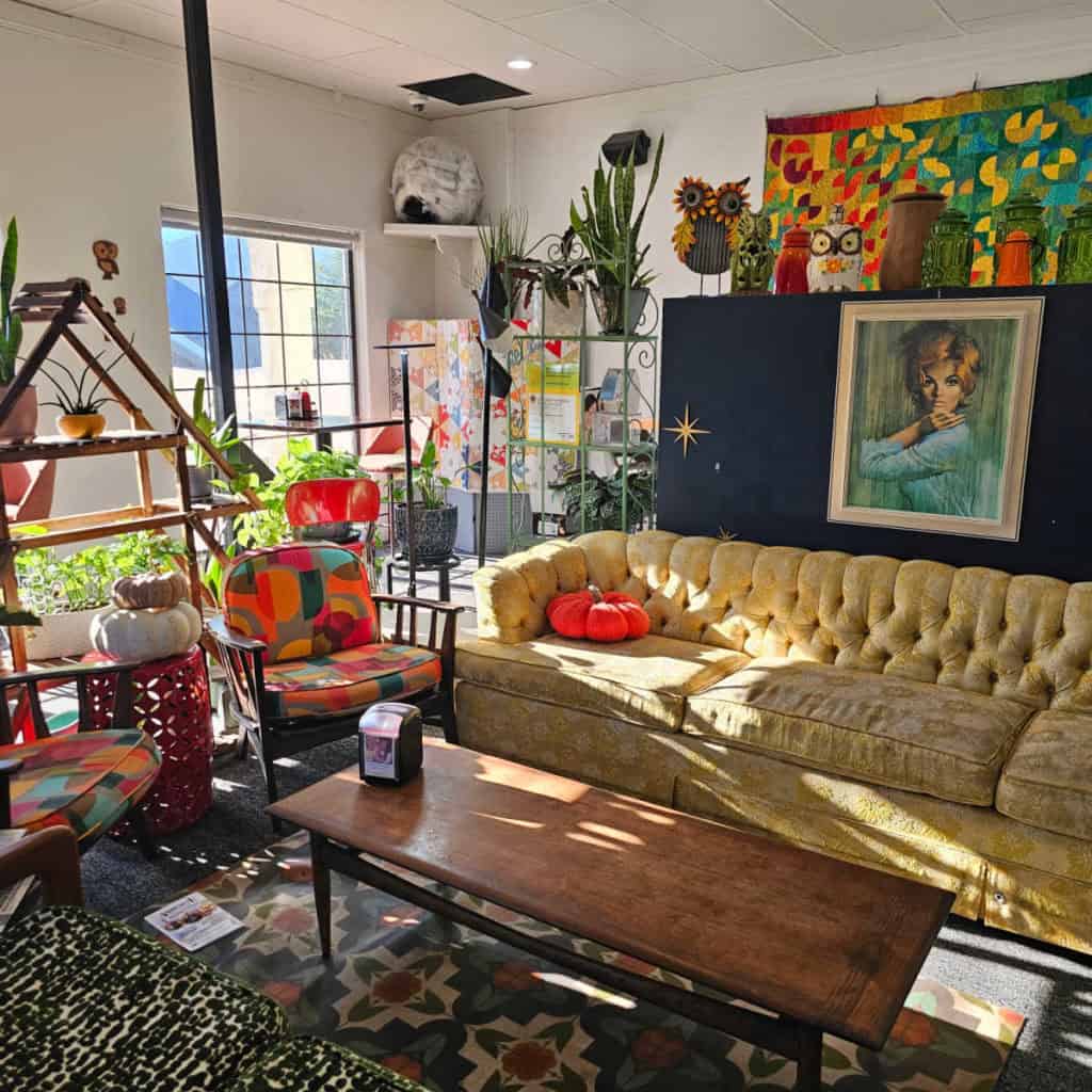 Bee's Bakery Cafe interior with plants, gold couch, table, funky chairs, and cool art all over