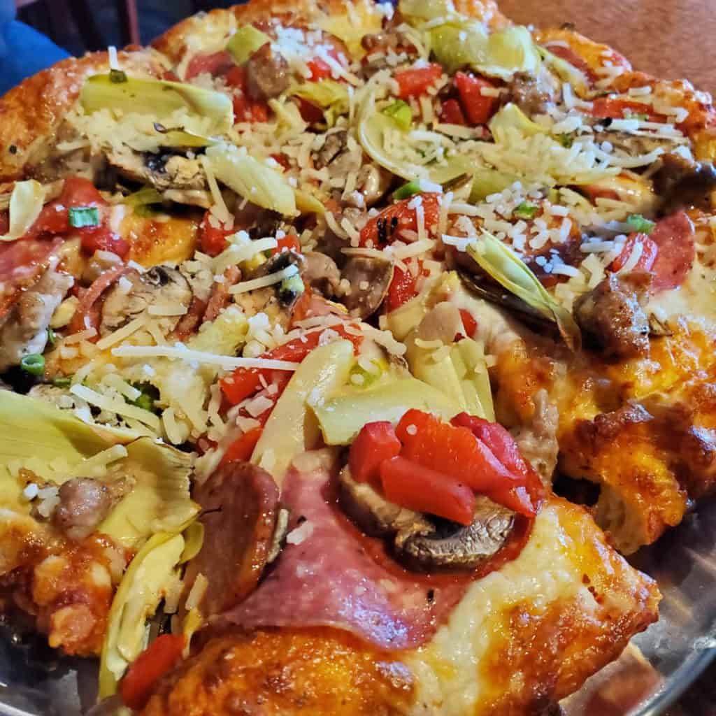 Me n Eds pizza with meat, peppers, and artichokes